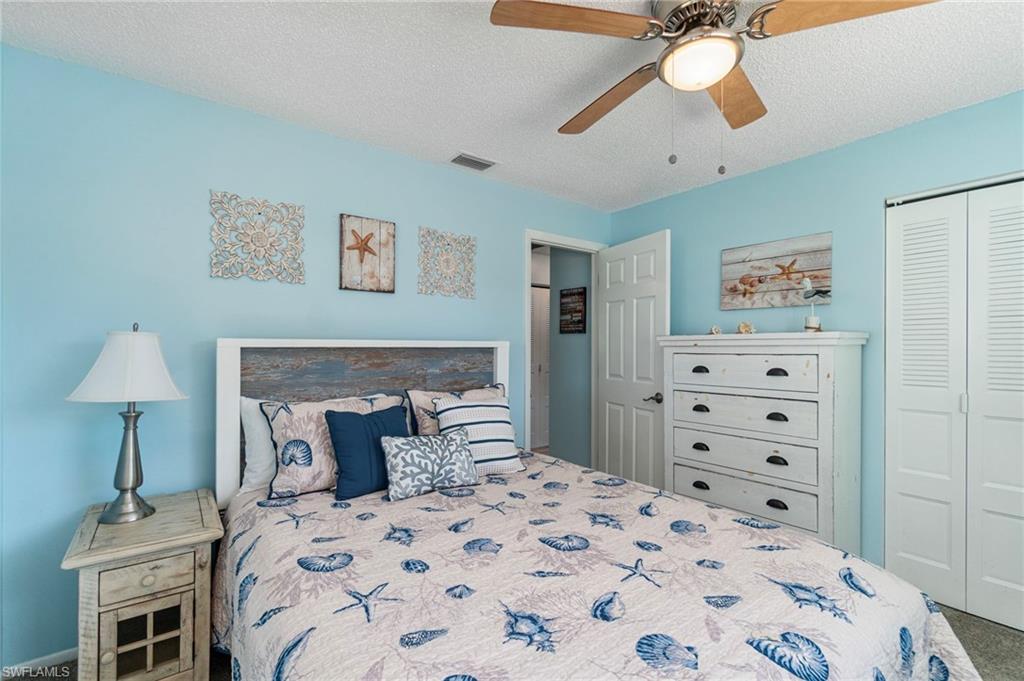 Bedroom with carpet, a closet, a textured ceiling, and a ceiling fan