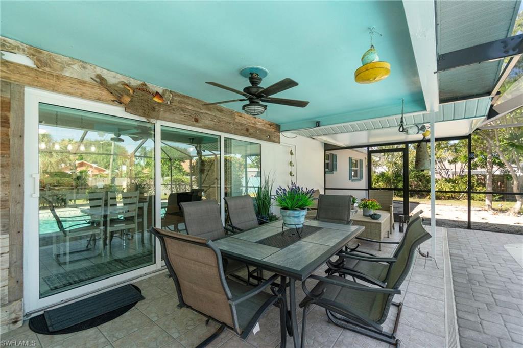 View of patio featuring ceiling fan, glass enclosure, and outdoor dining area