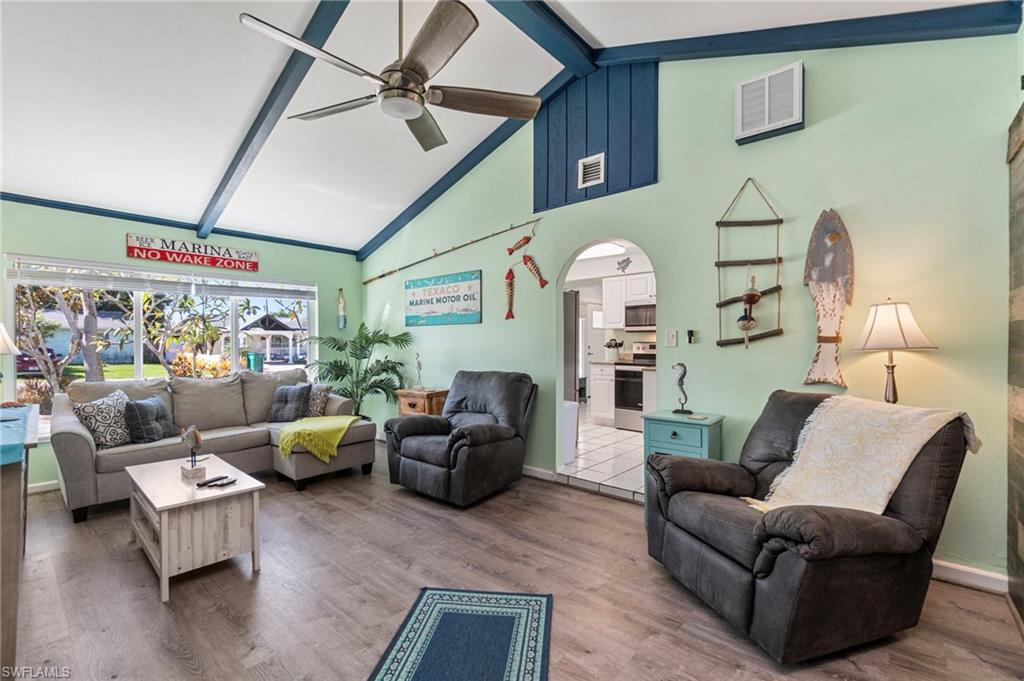Living room with beamed ceiling, wood finished floors, high vaulted ceiling, arched walkways, and ceiling fan
