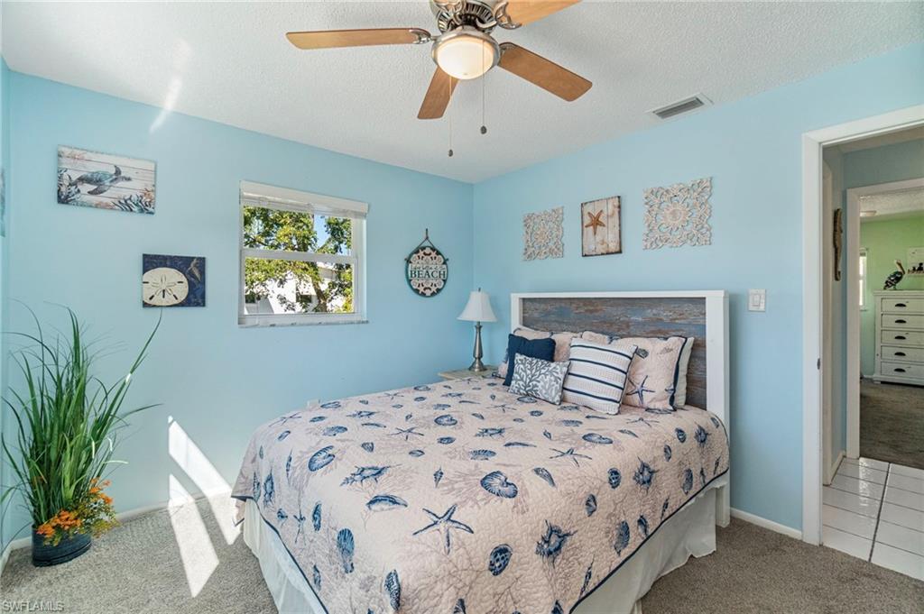 Bedroom featuring carpet flooring, a textured ceiling, a ceiling fan, and tile patterned floors