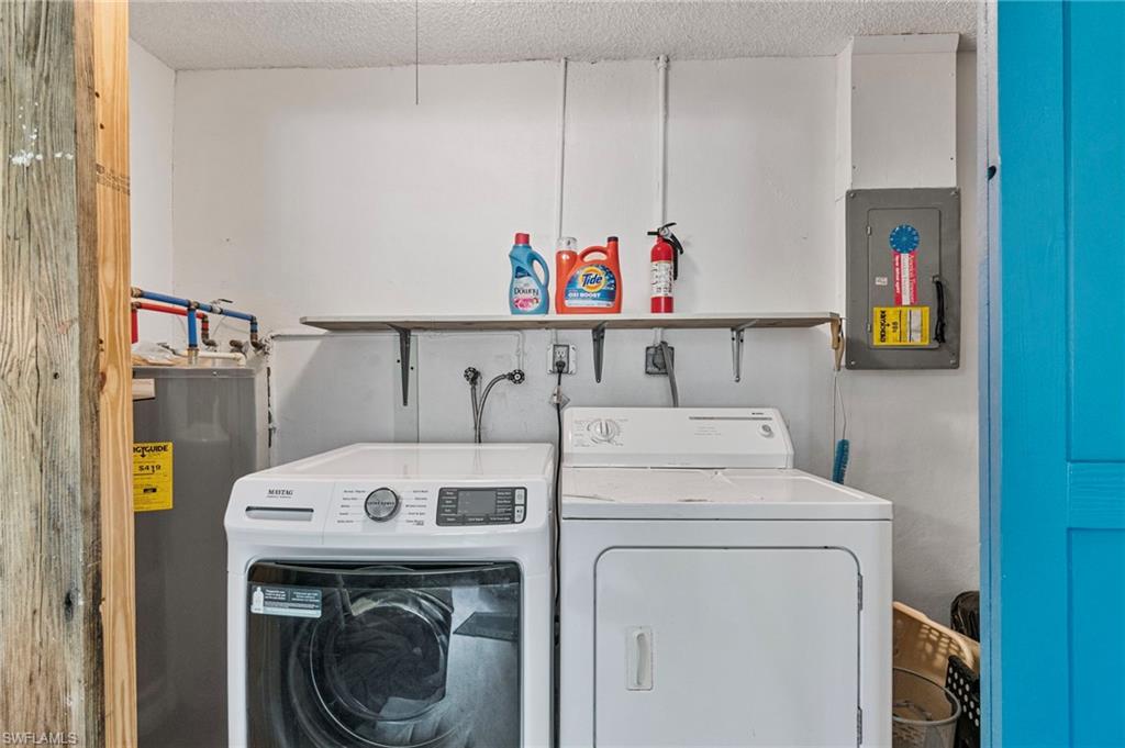 Laundry area featuring electric panel, electric water heater, washing machine and clothes dryer, and a textured ceiling