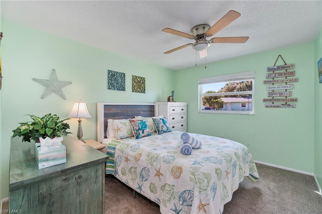 Bedroom featuring a textured ceiling, dark colored carpet, and a ceiling fan