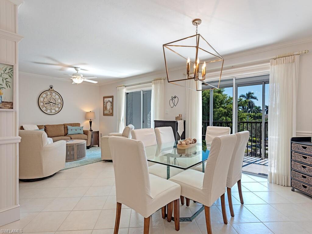 Dining area with light tile patterned floors, crown molding, ceiling fan, and a chandelier