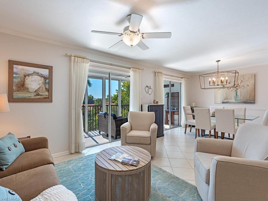 Tiled living area with ornamental molding, a chandelier, and ceiling fan