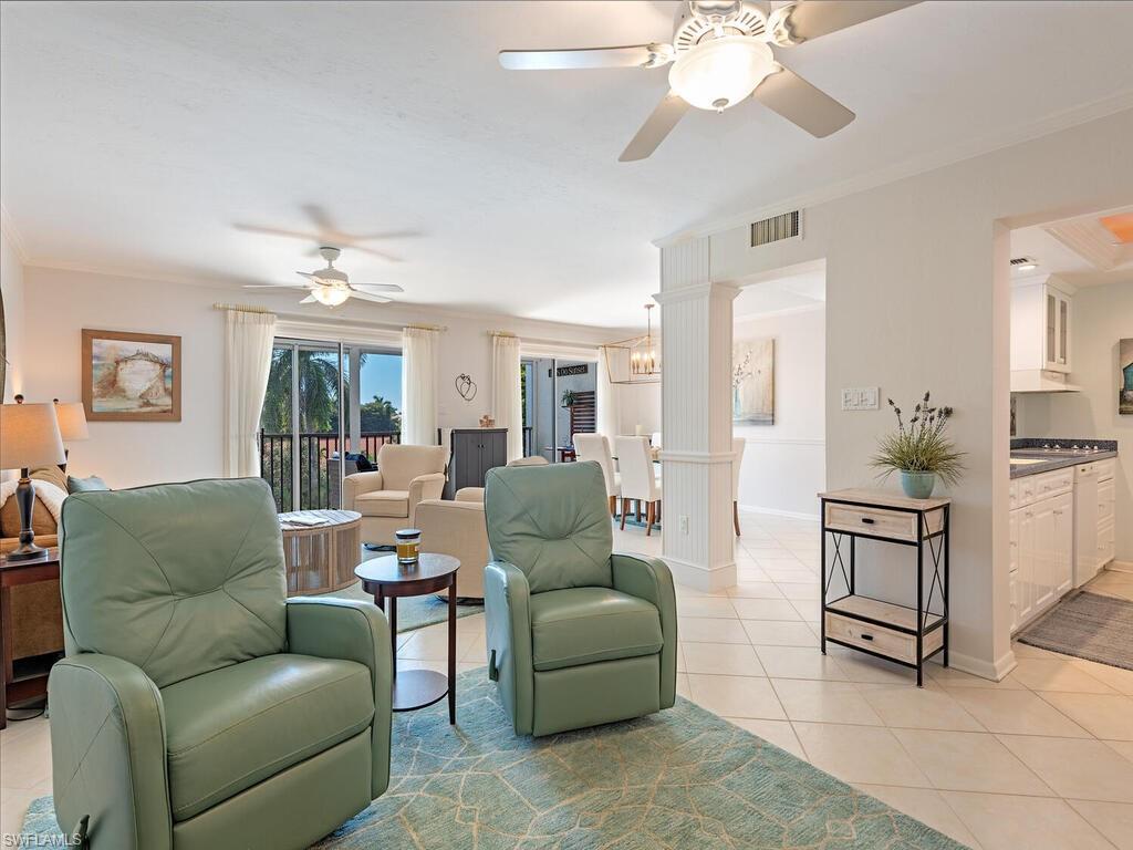 Living area featuring light tile patterned floors, ornamental molding, a ceiling fan, and a chandelier