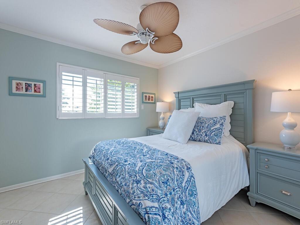 Bedroom with crown molding, light tile patterned floors, and a ceiling fan