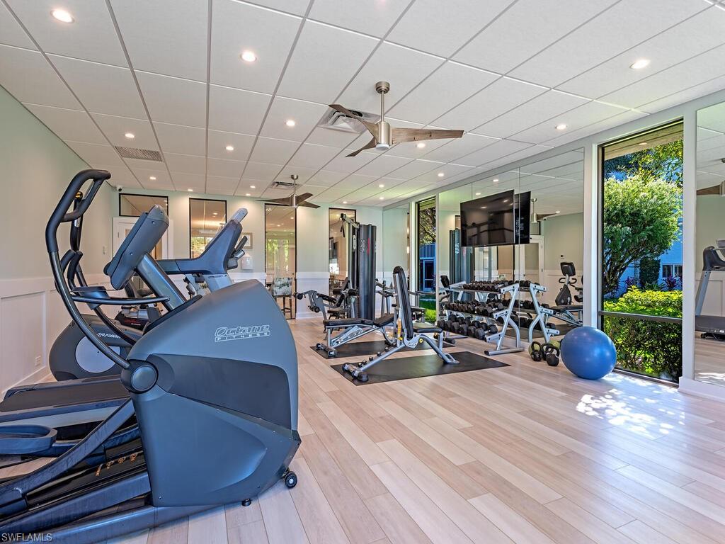 Exercise room with a drop ceiling, wainscoting, recessed lighting, and a decorative wall