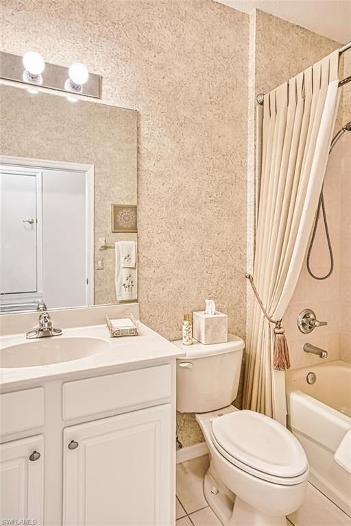 Full bath with light tile patterned floors, shower / bath combo, vanity, and wallpapered walls