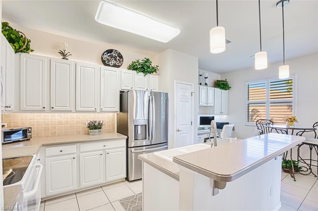 Kitchen featuring stainless steel refrigerator with ice dispenser, white cabinetry, range with electric cooktop, decorative light fixtures, and light tile patterned floors