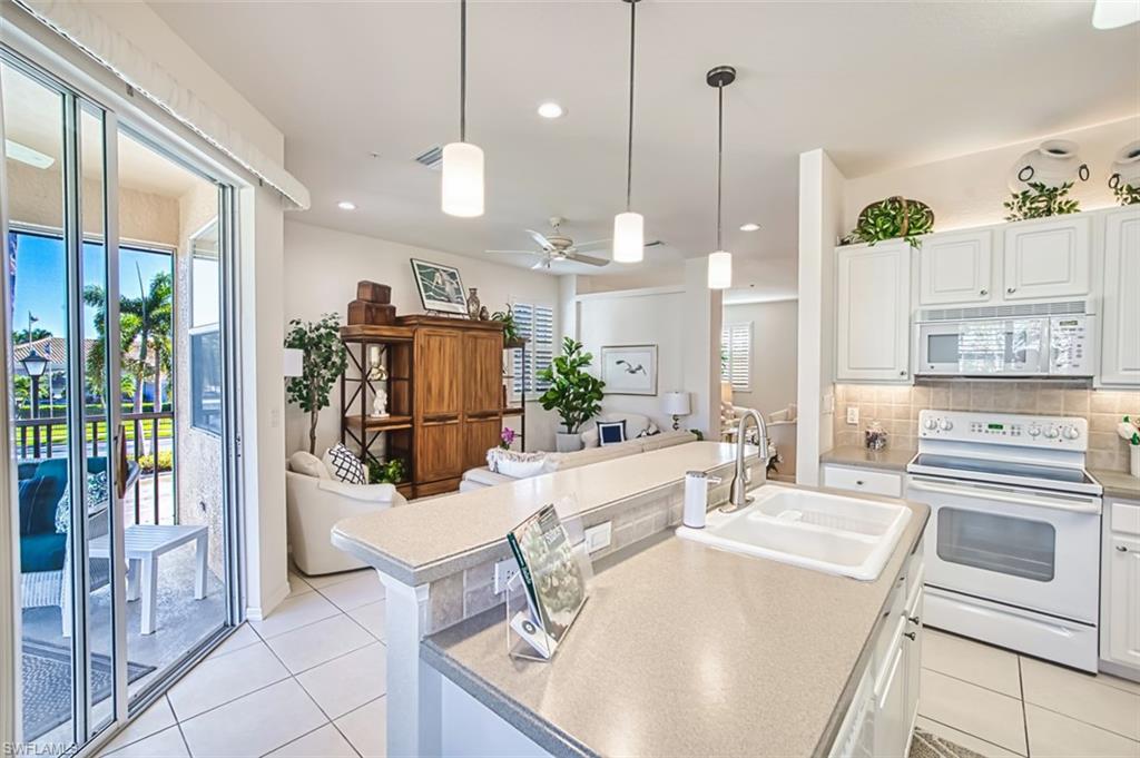 Kitchen with white cabinets, white appliances, hanging light fixtures, decorative backsplash, and recessed lighting