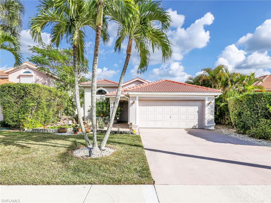 Mediterranean / spanish house with a tiled roof, driveway, stucco siding, a front lawn, and a garage