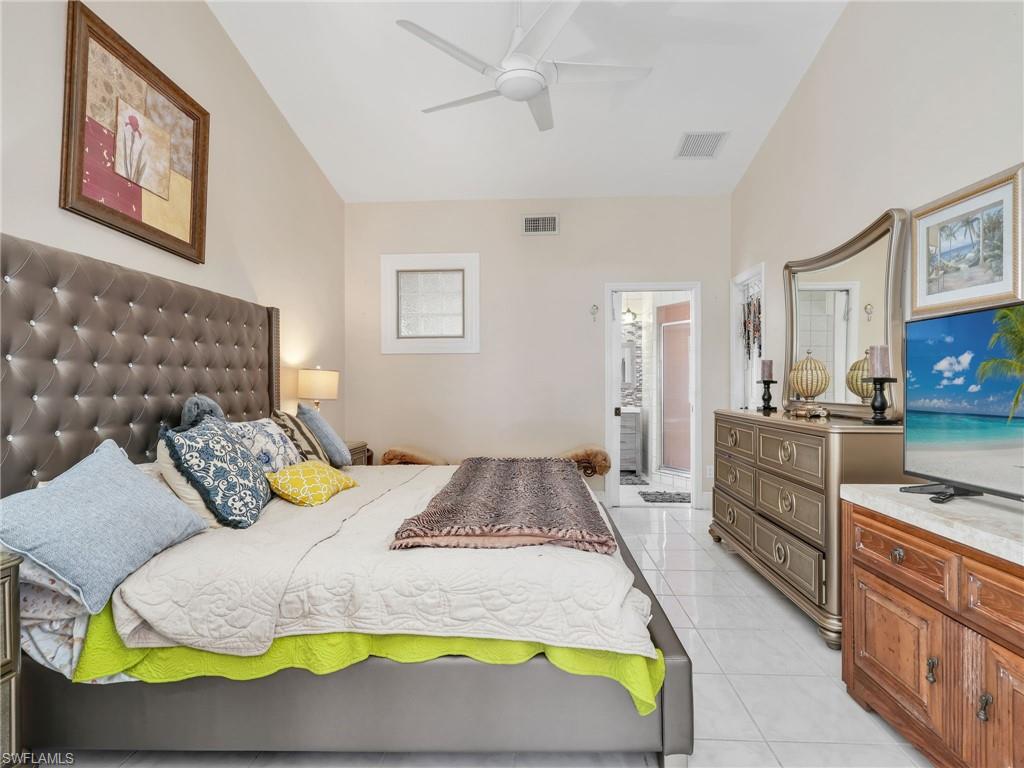 Bedroom featuring light tile patterned floors, ceiling fan, and ensuite bathroom