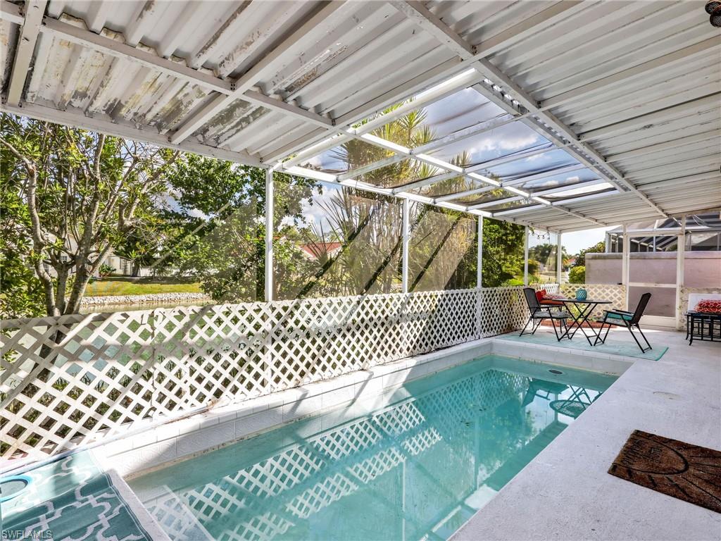 Screened pool enclosure with a lattice railing, a clear panel roof section, and a concrete pool deck