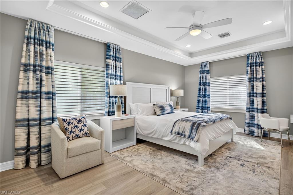 Bedroom with a tray ceiling, wood finished floors, recessed lighting, and ceiling fan