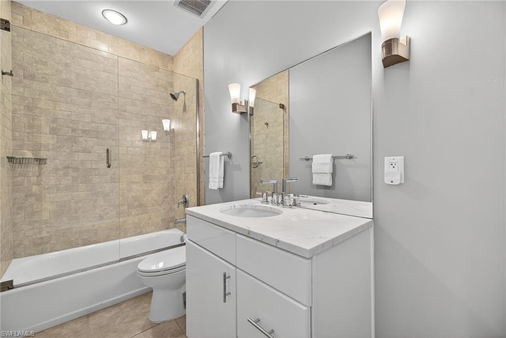 Full bath with vanity, bath / shower combo with glass door, and light tile patterned floors