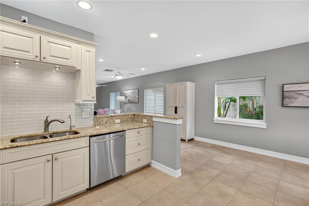 Kitchen with light stone countertops, decorative backsplash, stainless steel dishwasher, healthy amount of natural light, and recessed lighting