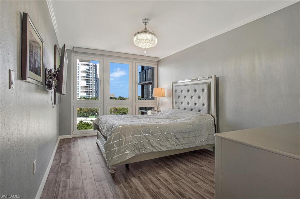 Bedroom with wood tiled floors, ornamental molding, and a chandelier