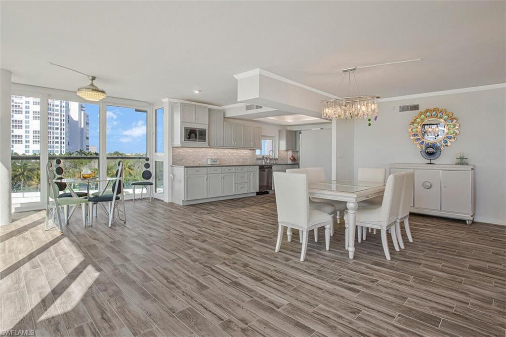 Dining area with wood finish floors, ornamental molding, a chandelier, a view of city, and recessed lighting