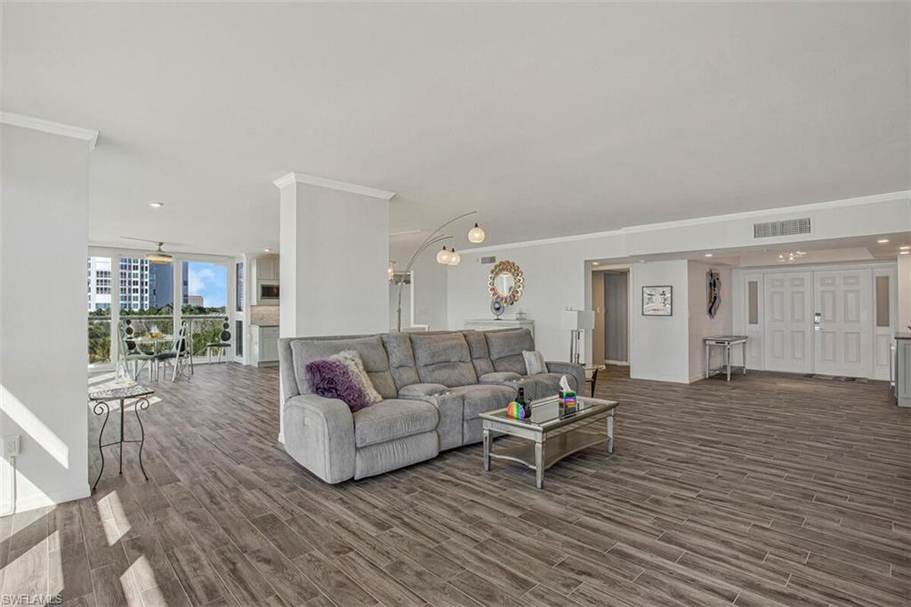 Living room featuring crown molding, dark wood-style floors, a wall of windows, and recessed lighting