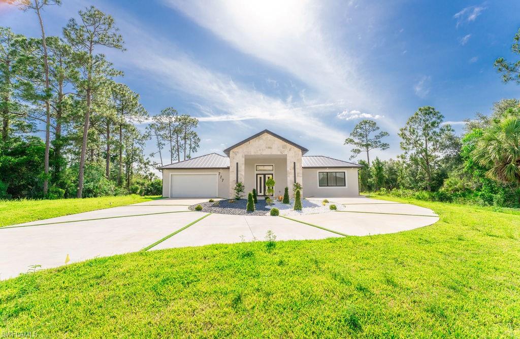 View of front of home featuring a metal roof, a front lawn, driveway, and a garage