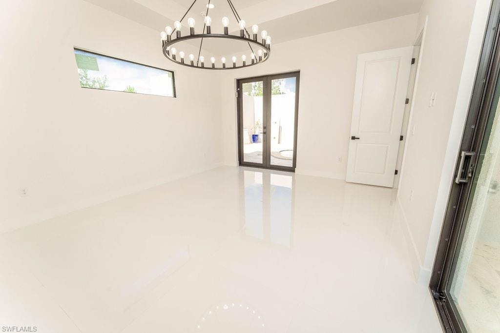 Unfurnished room featuring french doors and a chandelier
