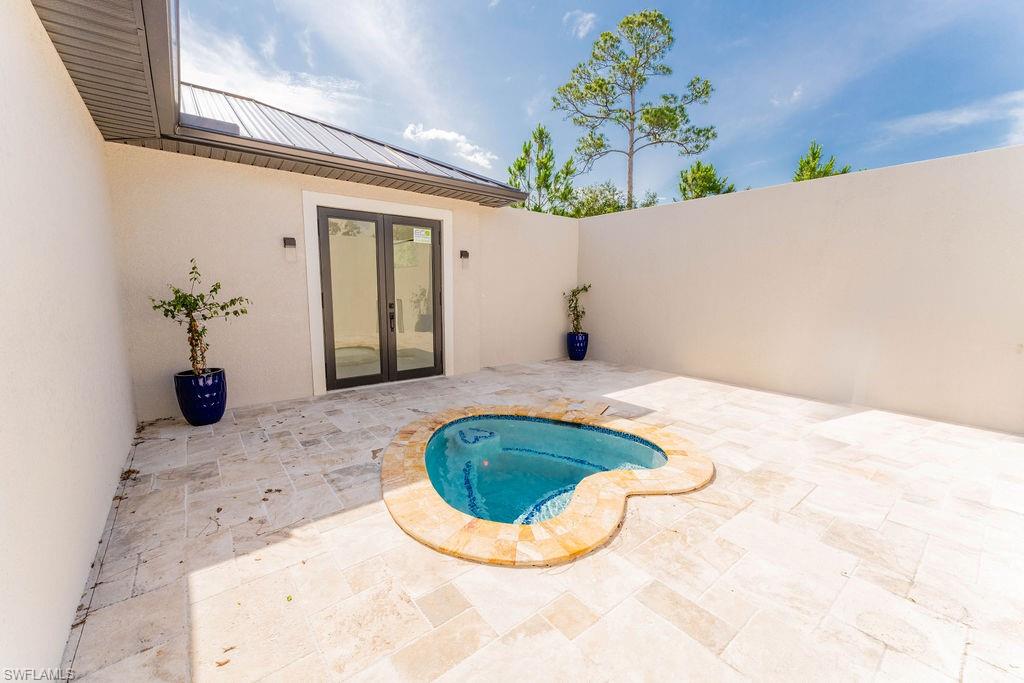 View of pool with french doors, a patio, and an in-ground hot tub