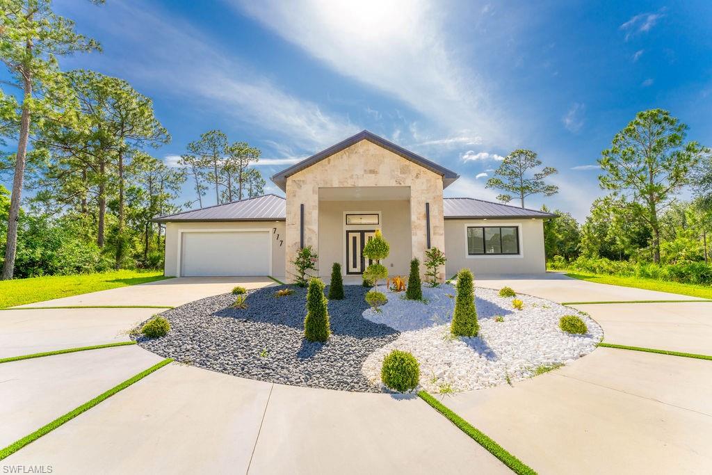 View of front of property with a metal roof, concrete driveway, a standing seam roof, and a garage