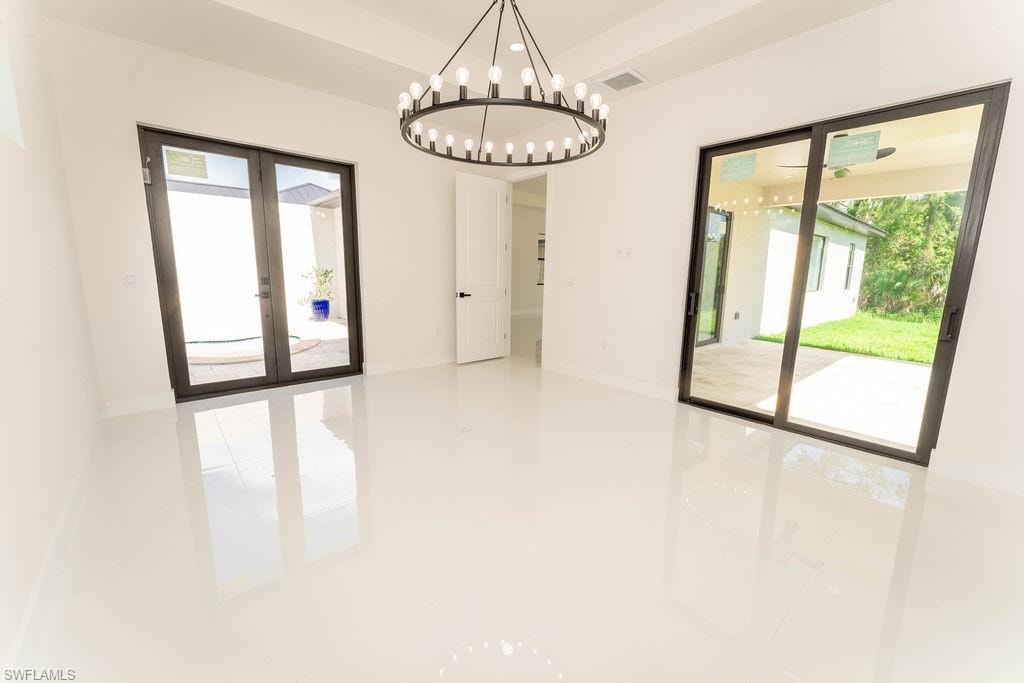 Unfurnished dining area with french doors, plenty of natural light, and a chandelier