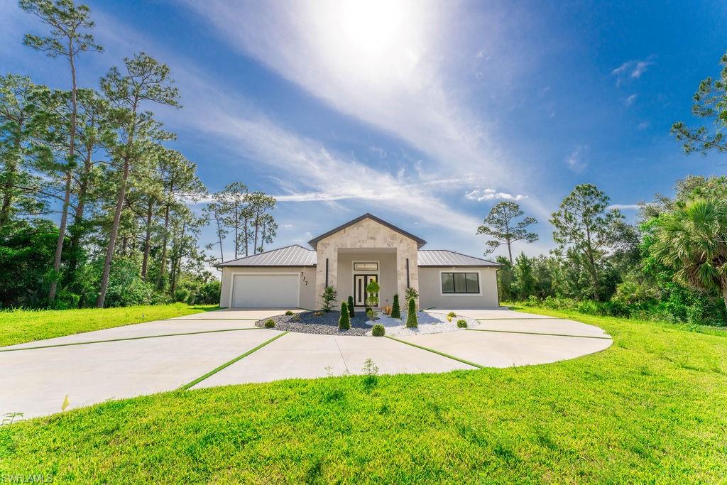 View of front of property with a metal roof, a front lawn, and concrete driveway