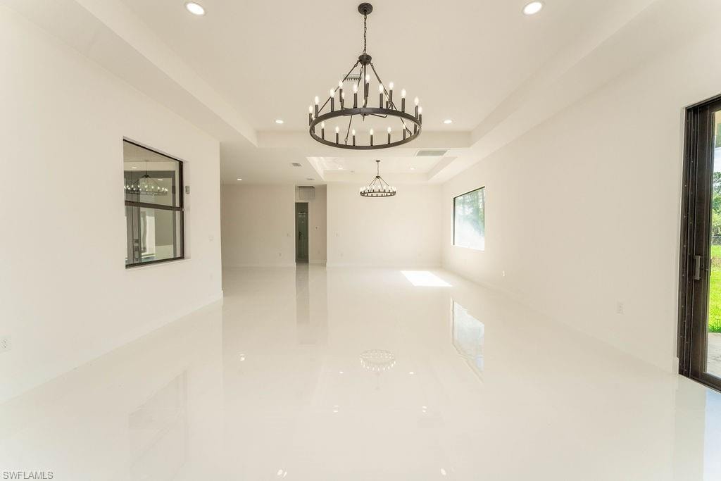 Unfurnished room with a tray ceiling, recessed lighting, and a chandelier