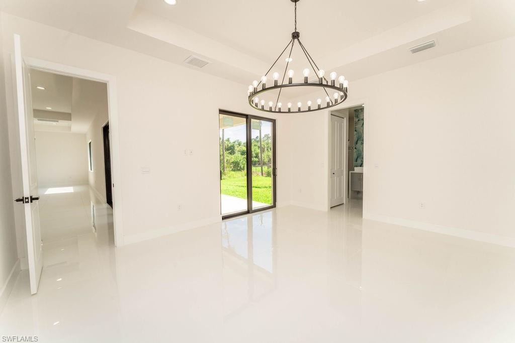 Unfurnished room with a tray ceiling, recessed lighting, and a chandelier