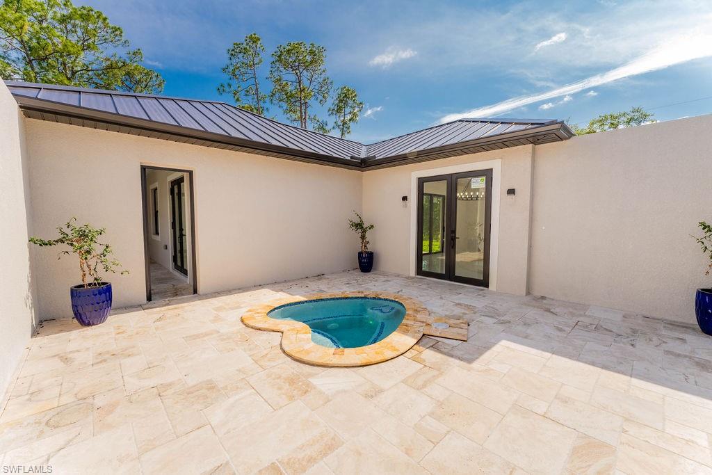 View of swimming pool with a patio area, french doors, and an in-ground hot tub