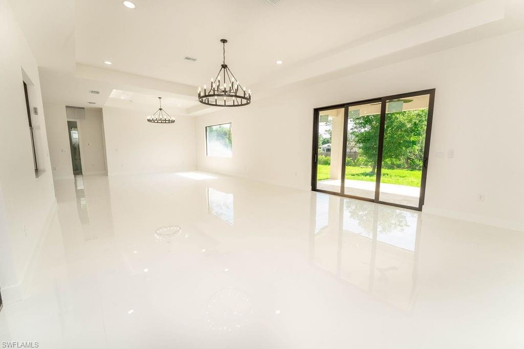 Empty room featuring a tray ceiling, recessed lighting, and a chandelier