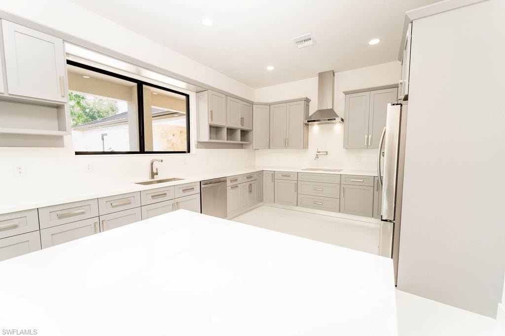 Kitchen featuring open shelves, gray cabinetry, wall chimney range hood, stainless steel appliances, and recessed lighting