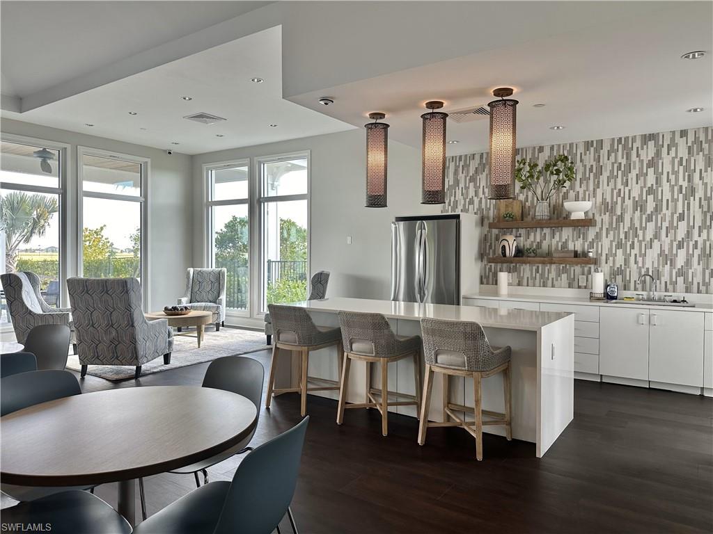 Kitchen with white cabinetry, open shelves, freestanding refrigerator, a kitchen breakfast bar, and light stone countertops