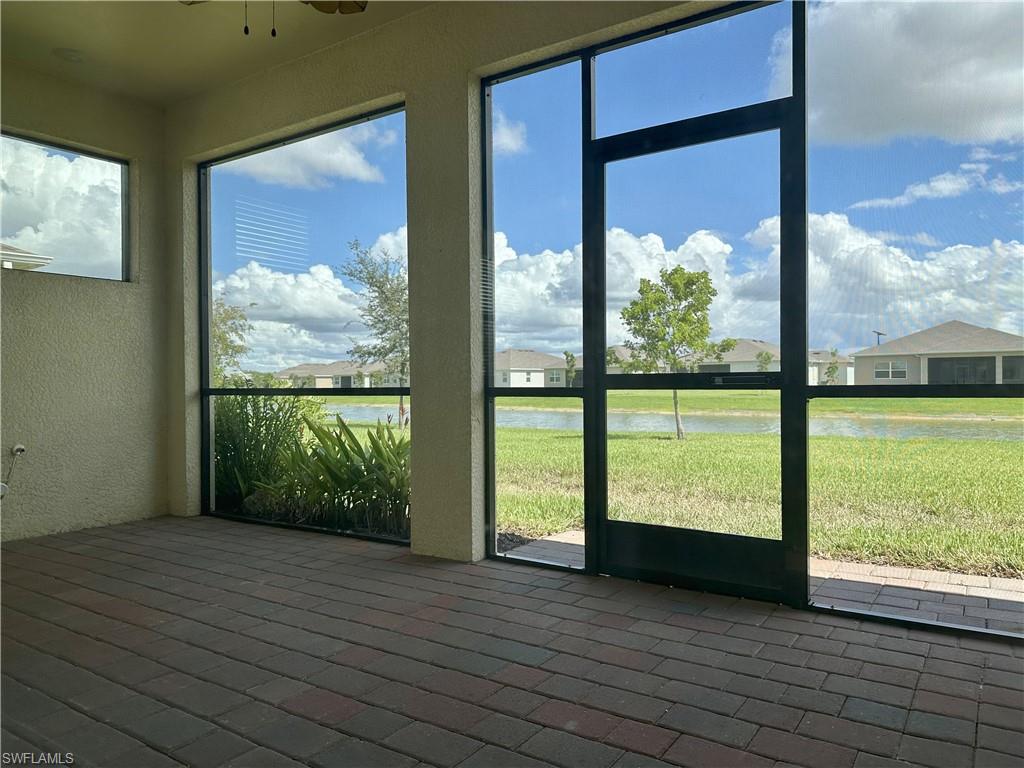 Unfurnished sunroom featuring a water view, ceiling fan, and a residential view