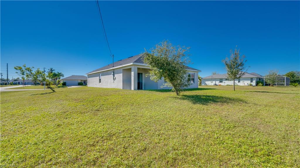 View of side of home with a lawn and stucco siding