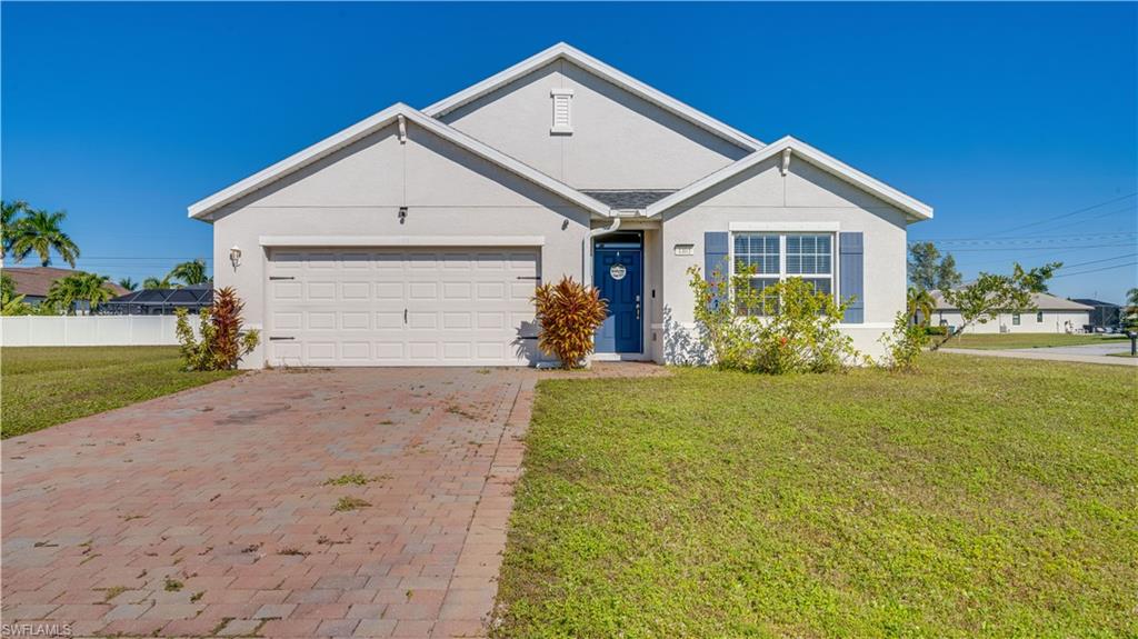 Ranch-style home featuring stucco siding, decorative driveway, and an attached garage