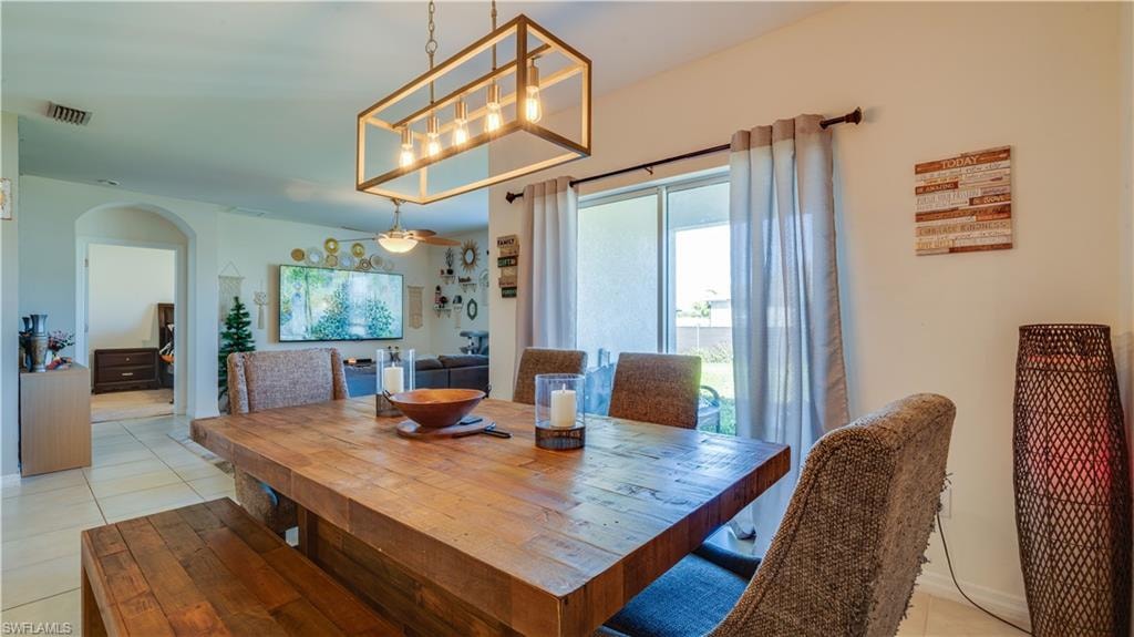 Dining space featuring light tile patterned floors and arched walkways