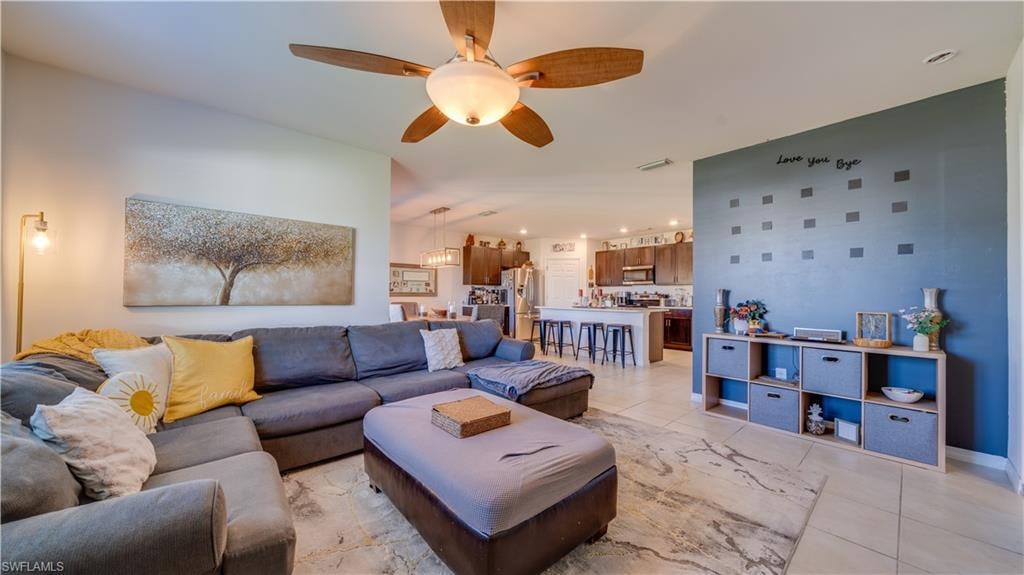 Living area featuring light tile patterned floors, ceiling fan, and recessed lighting