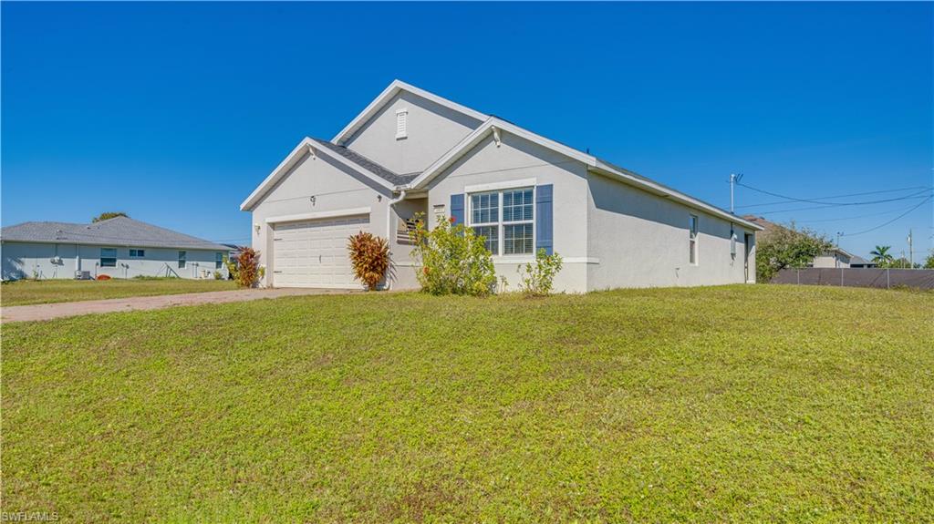 Ranch-style house featuring a front lawn, stucco siding, and driveway