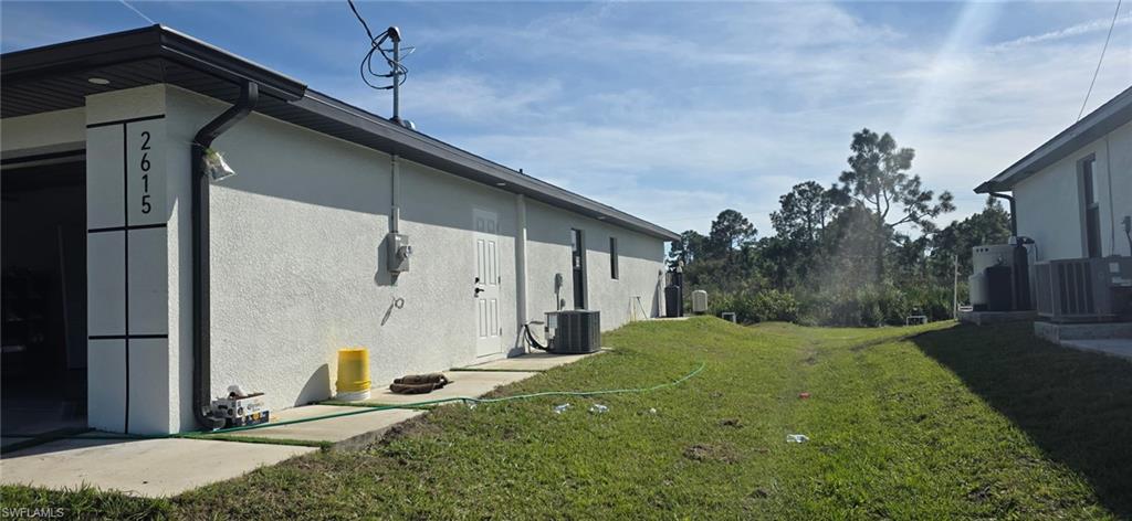 View of property exterior with a lawn and stucco siding