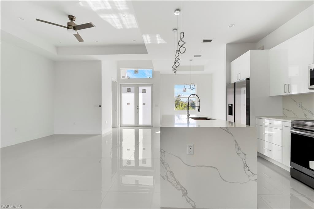 Kitchen with modern cabinets, white cabinetry, and light stone counters
