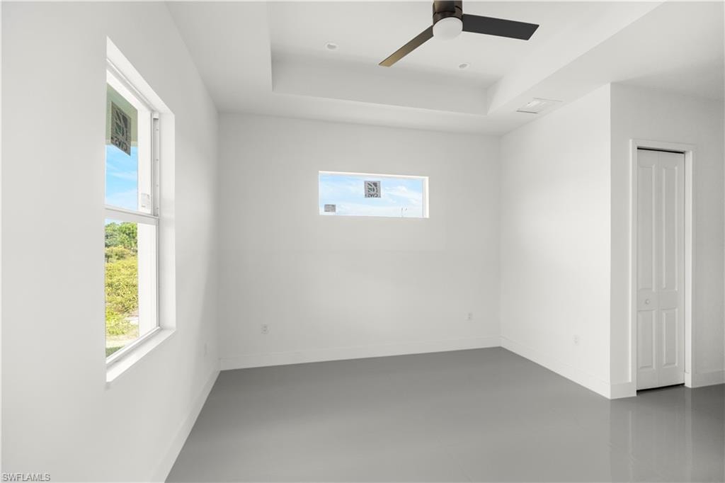 Empty room with ceiling fan, a tray ceiling, and recessed lighting