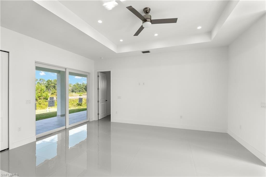 Spare room featuring a tray ceiling, recessed lighting, finished concrete flooring, and a ceiling fan