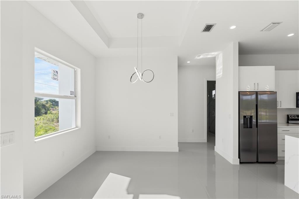 Unfurnished dining area with recessed lighting and a raised ceiling