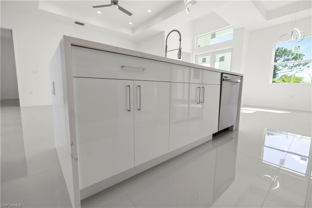 Kitchen view of modern cabinets, a tray ceiling, stainless steel dishwasher, pendant lighting, and recessed lighting