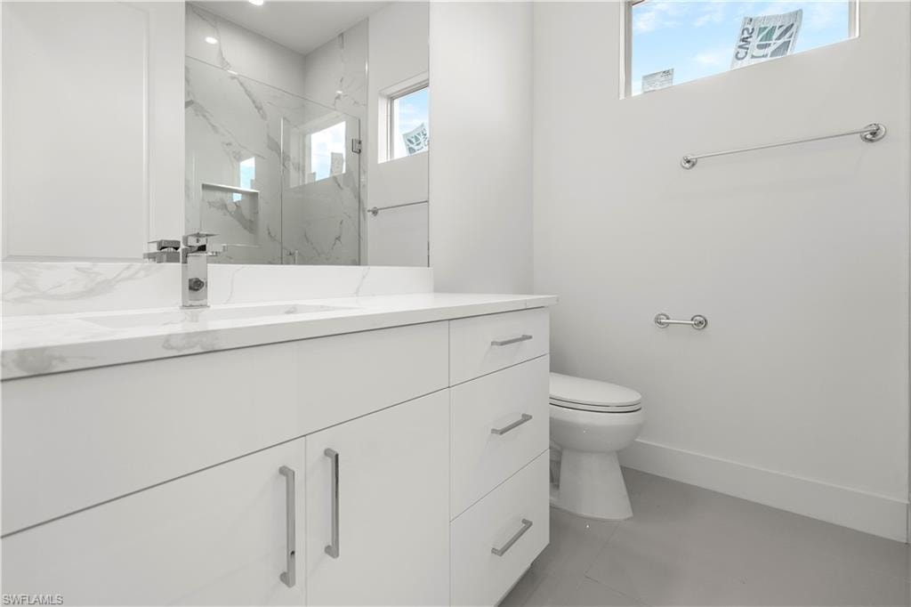 Bathroom featuring vanity and a marble finish shower