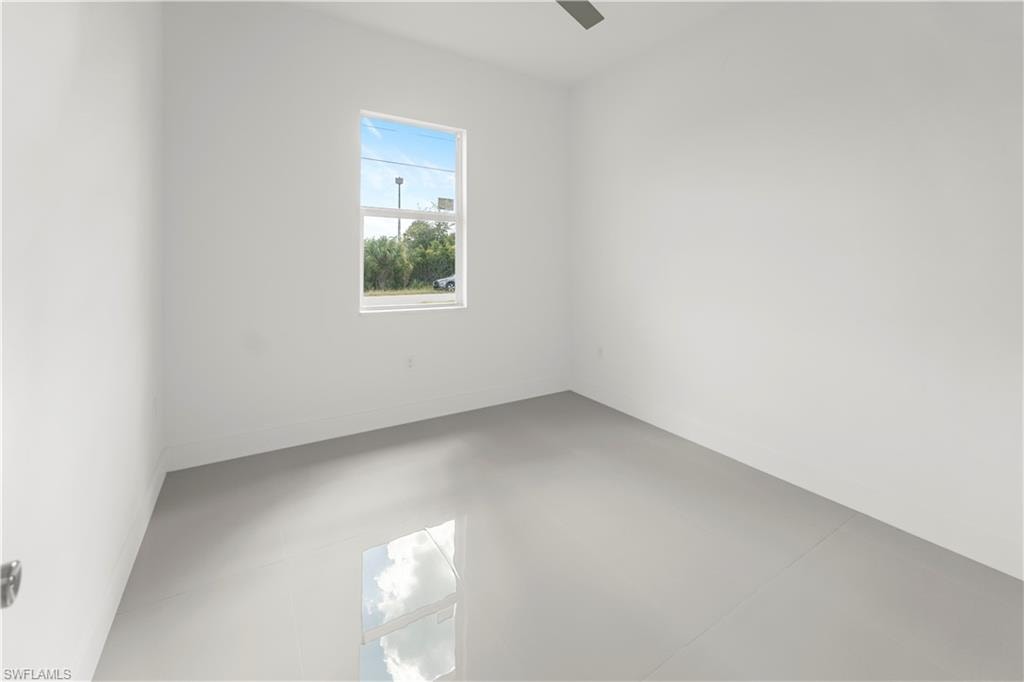 Empty room featuring finished concrete floors and baseboards