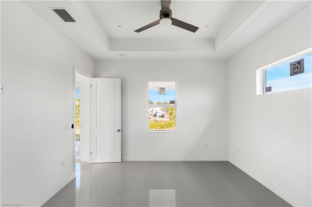 Spare room with plenty of natural light, a raised ceiling, and ceiling fan